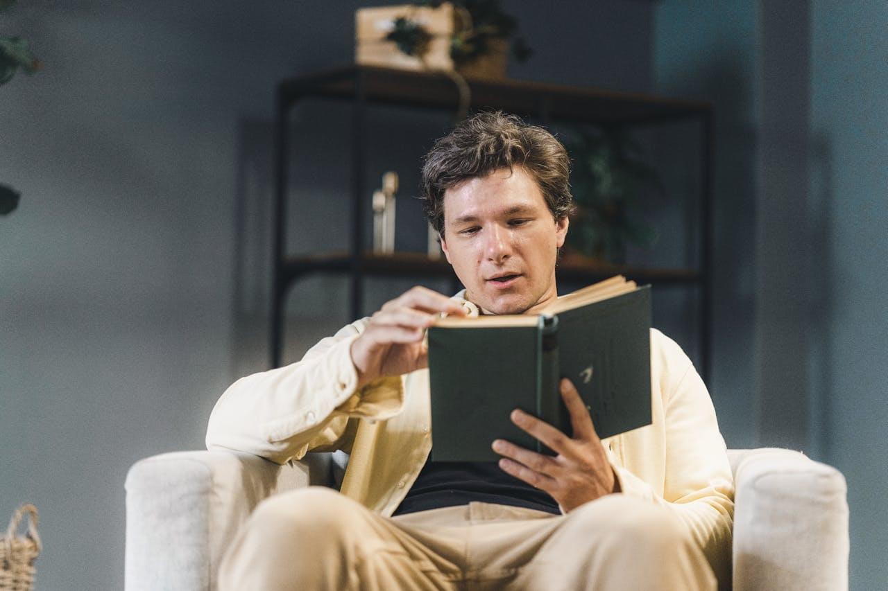 Человек читает книгу в кресле
